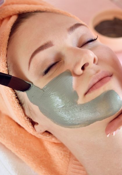 Face peeling mask, spa beauty treatment, skincare. Woman getting facial care by beautician at spa salon, side view, close-up